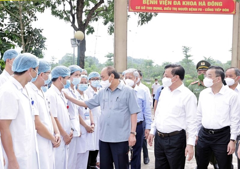 Chủ tịch nước Nguyễn Xuân Phúc thăm hỏi nhân viên y tế làm việc tại cơ sở thu dung, điều trị bệnh nhân Covid-19 của Bệnh viện đa khoa Hà Đông, tại phường Hoàng Liệt, quận Hoàng Mai. (Ảnh: TTXVN)